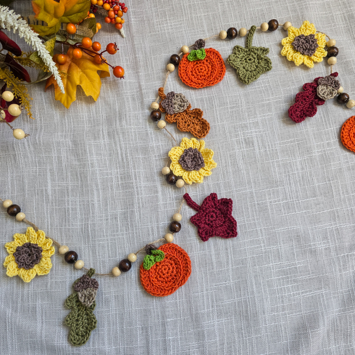 A colorful autumn harvest crochet garland with sunflowers, pumpkins, and leaves.