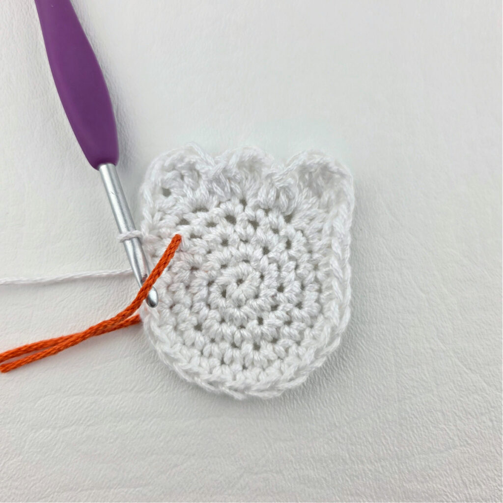 Making a white crochet ghost with a purple hook and green yarn to mark the stitch.