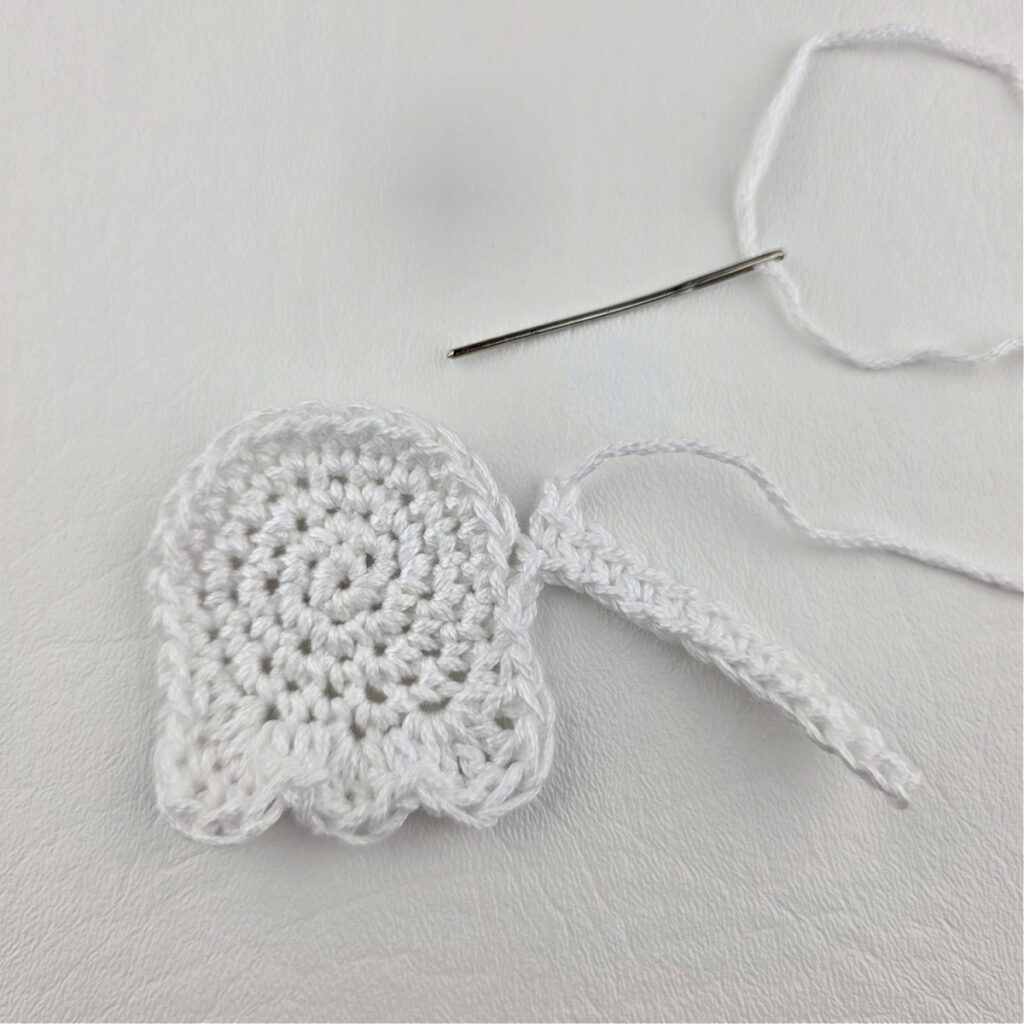 Seaming a white crochet ghost bookmark together.