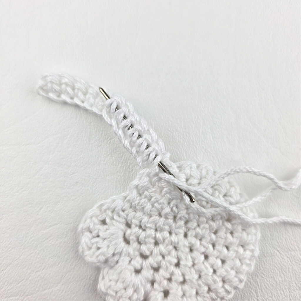 Seaming a white crochet ghost bookmark together.