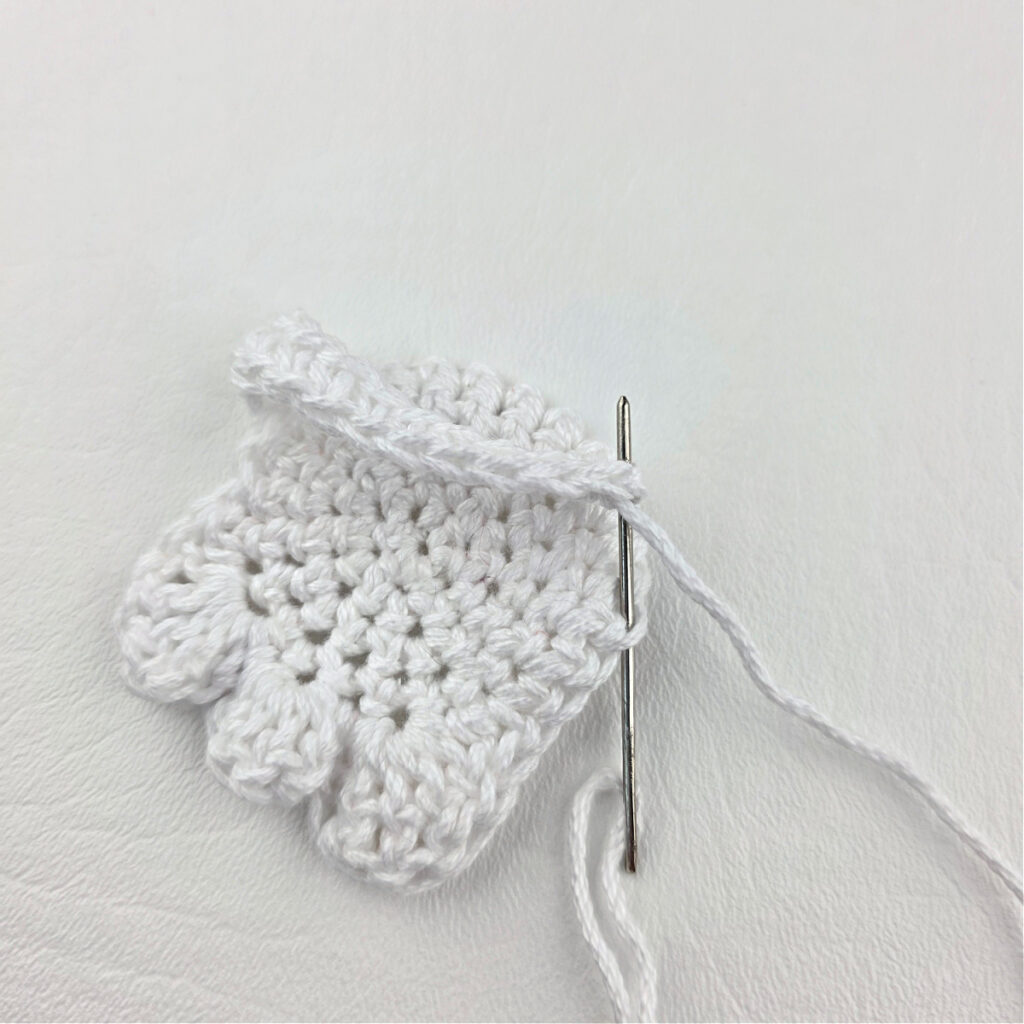 Seaming a white crochet ghost bookmark together.