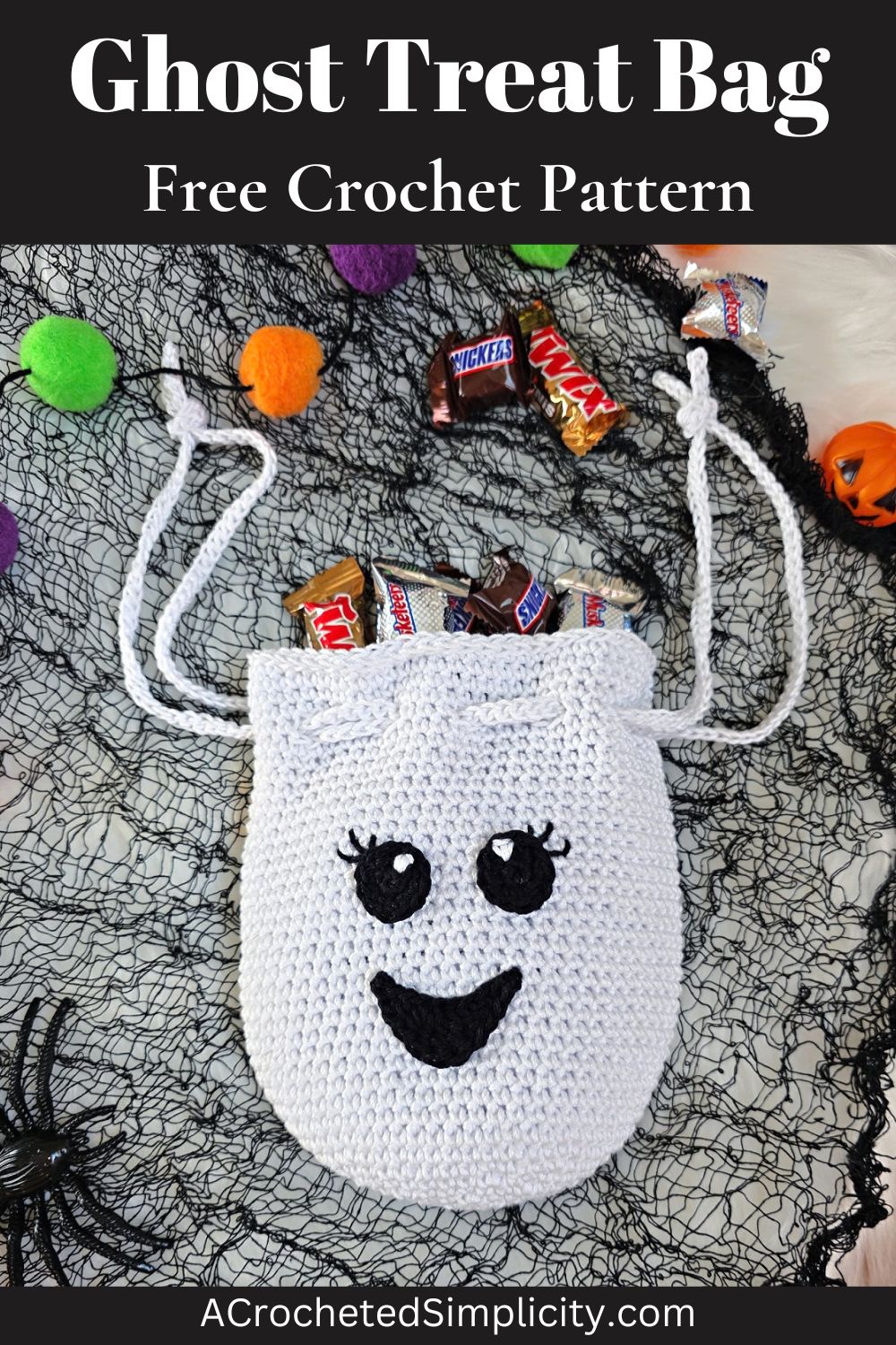 A crochet ghost treat bag full of candy against a white faux fur and web background.