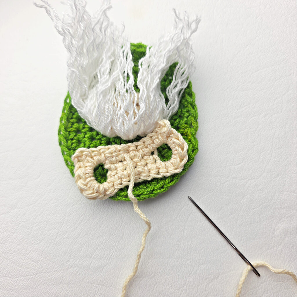 Attaching the holder of a candy cane on a crochet gnome.