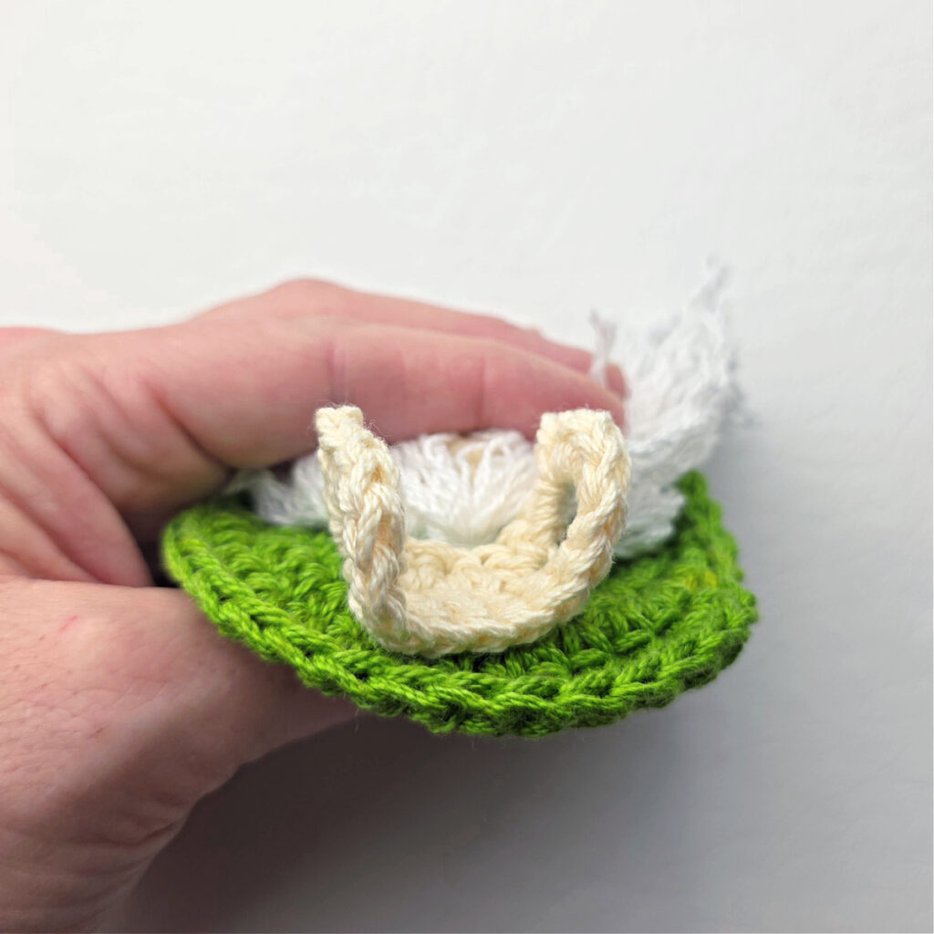 Attaching the holder of a candy cane on a crochet gnome.