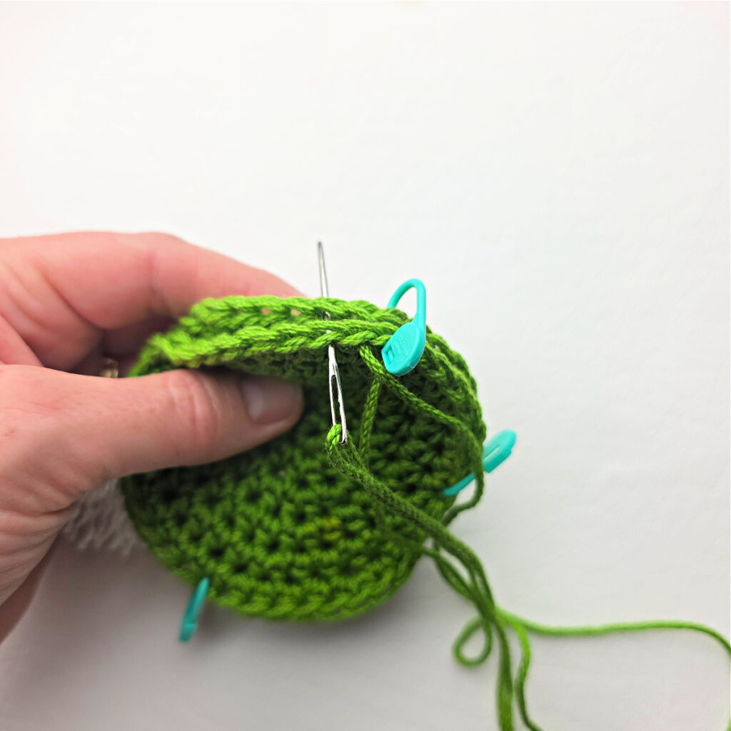 Sewing two green crochet circles together.