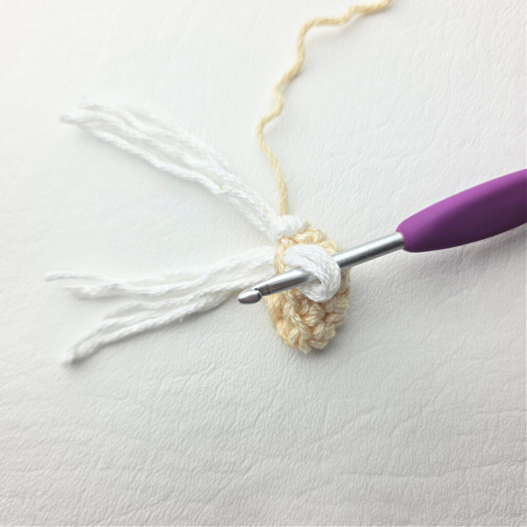 Attaching the beard of a crochet gnome.