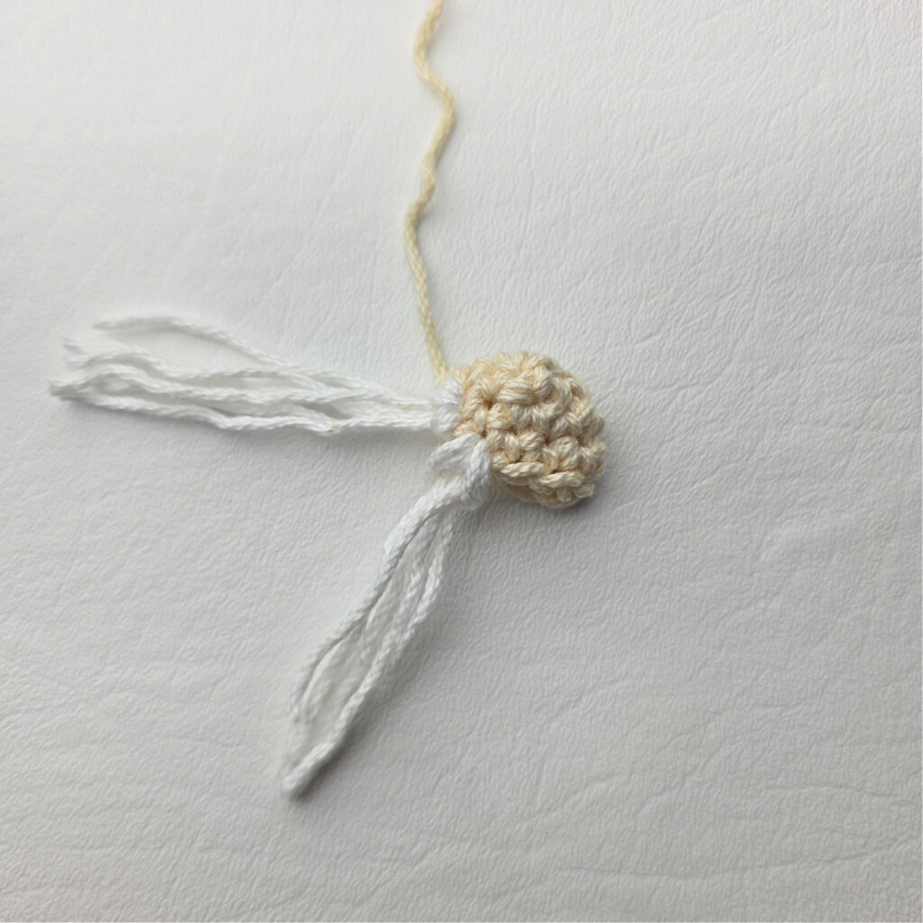 Attaching the beard of a crochet gnome.