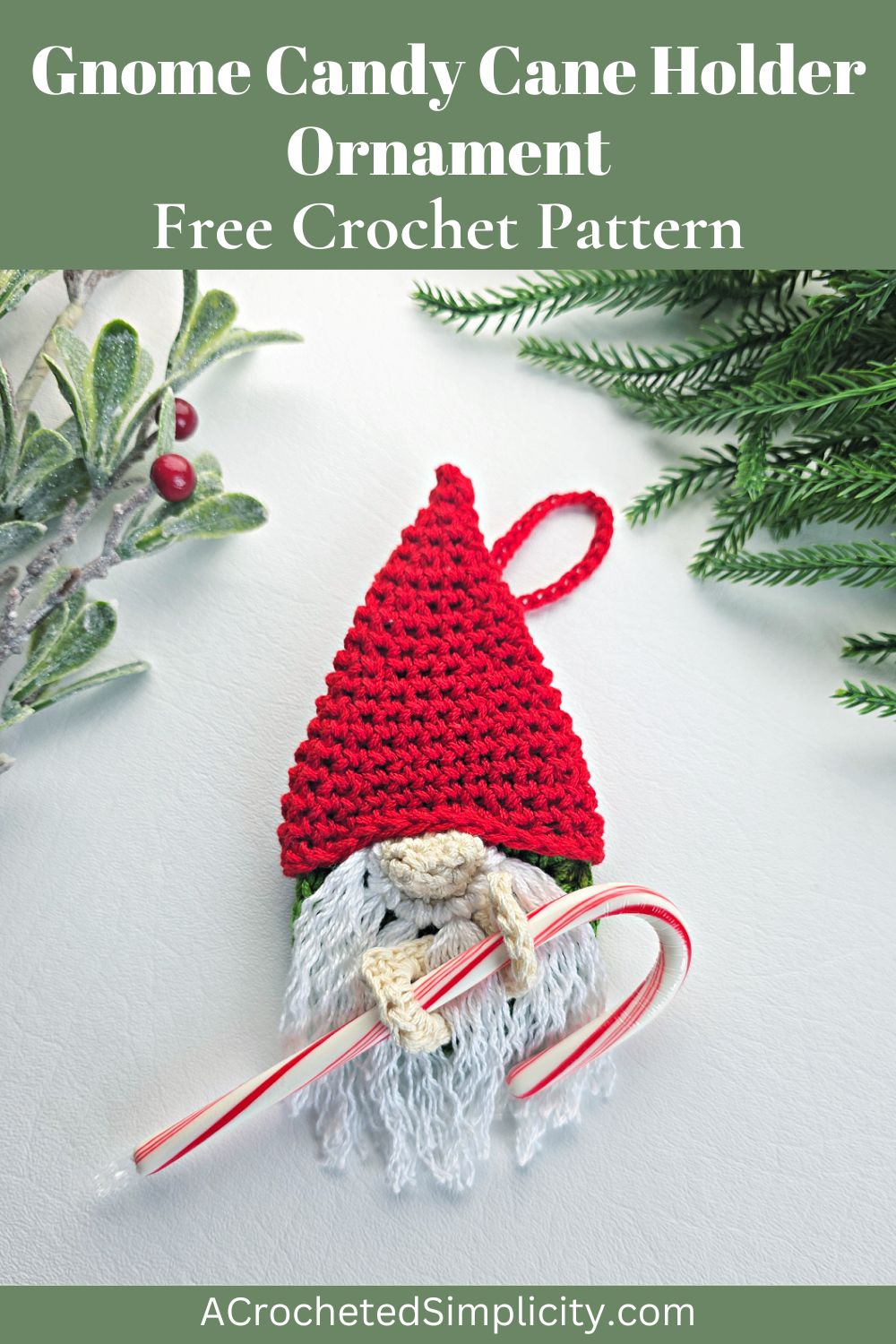 A crochet crochet gnome candy cane holder with a red santa hat next to green tinsel.