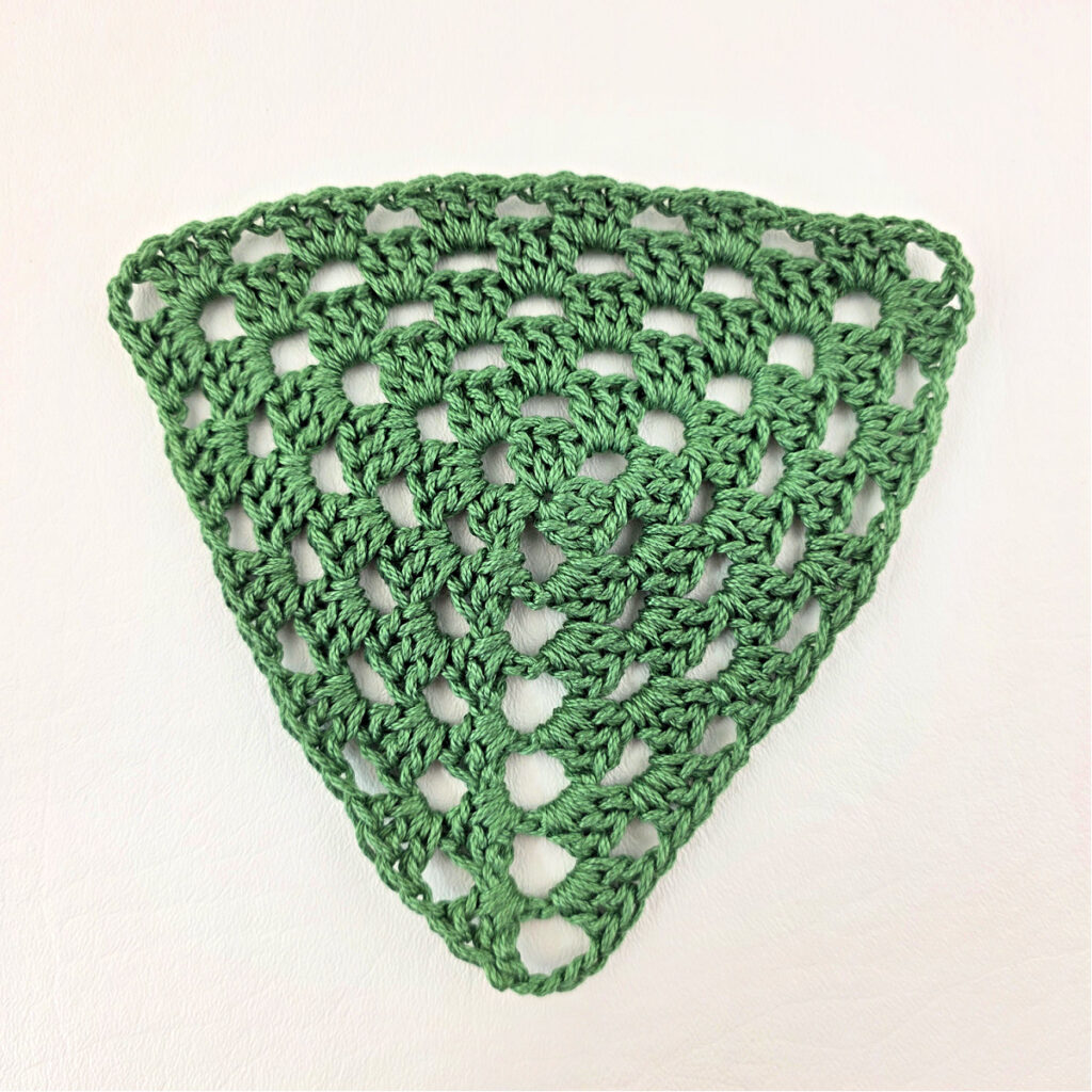 A green crochet granny triangle.