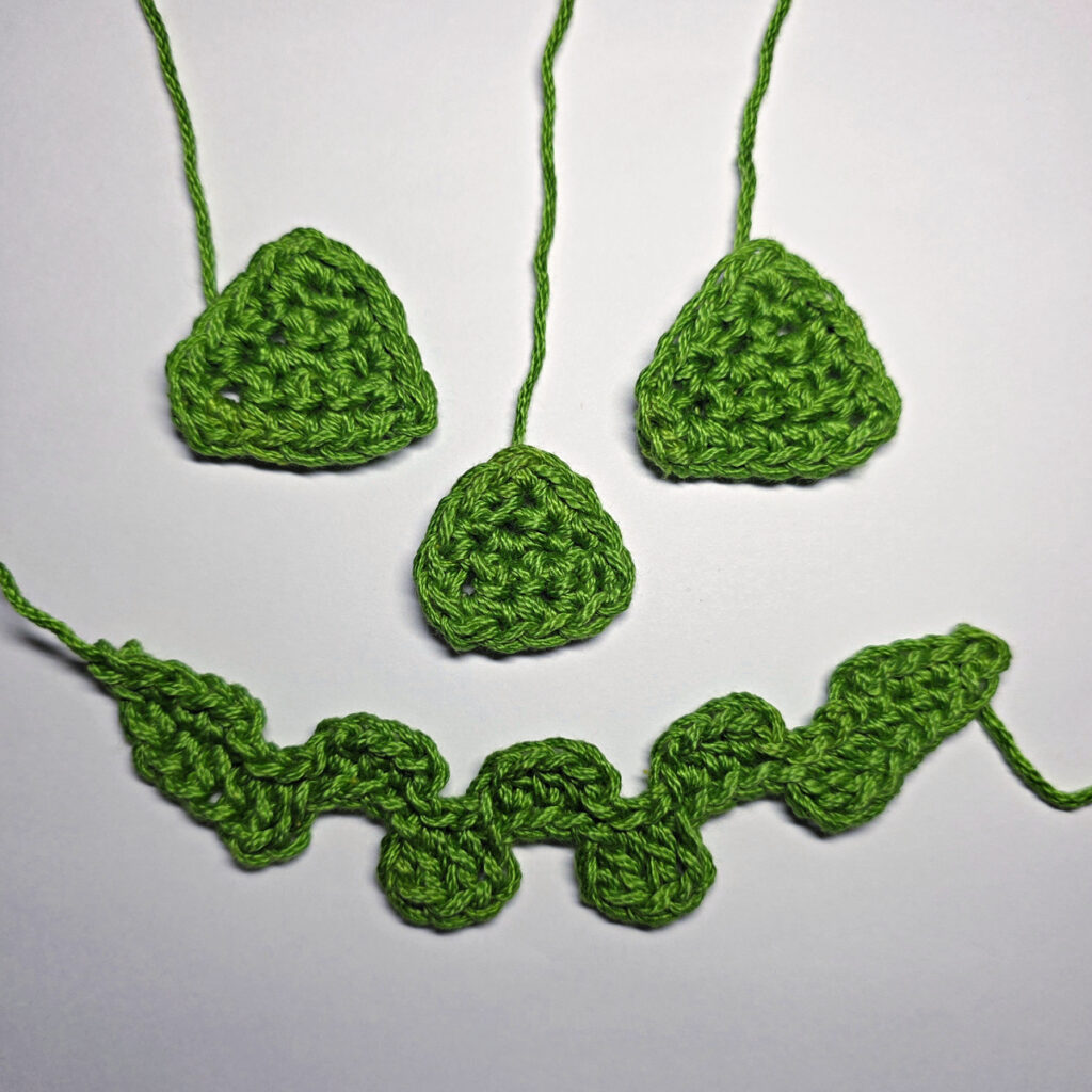 The face of a crochet jack-o-lantern in green yarn.