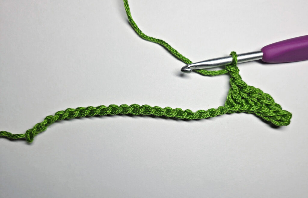 Working up a crochet jack-o-lantern mouth with green yarn.