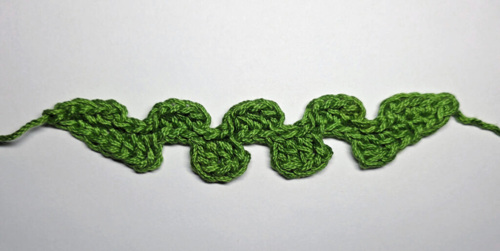 Working up a crochet jack-o-lantern mouth with green yarn.