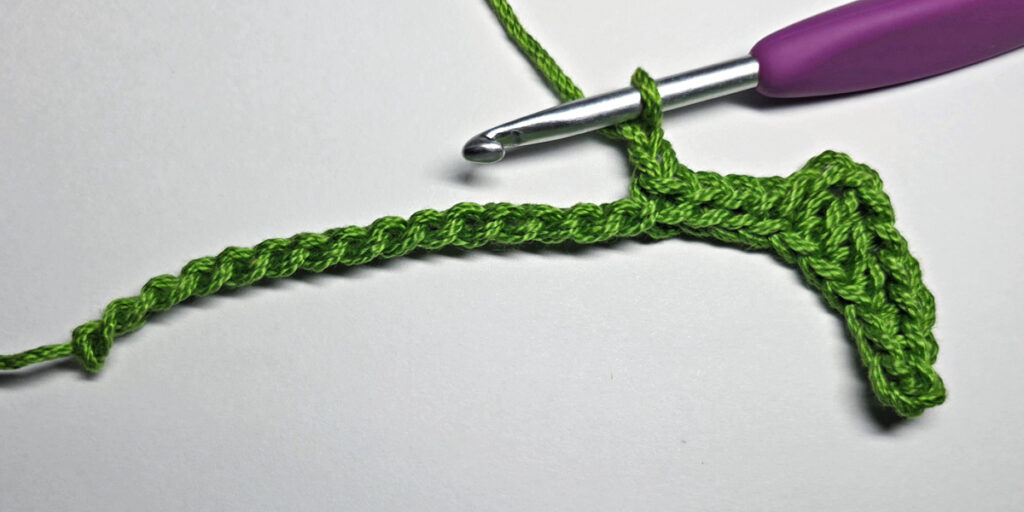 Working up a crochet jack-o-lantern mouth with green yarn.