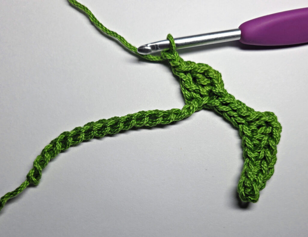 Working up a crochet jack-o-lantern mouth with green yarn.