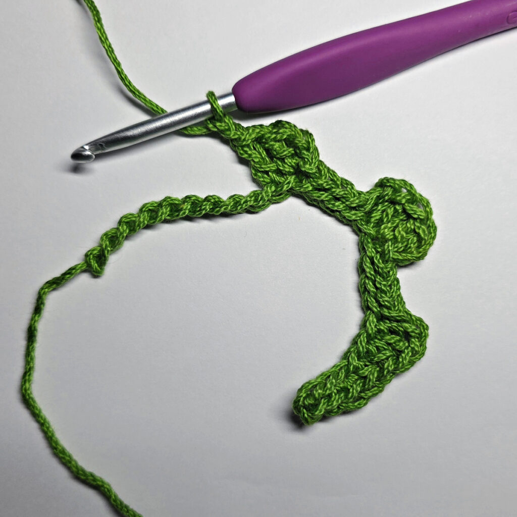 Working up a crochet jack-o-lantern mouth with green yarn.