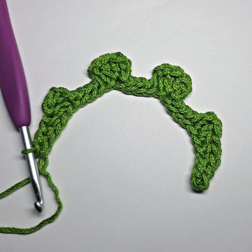 Working up a crochet jack-o-lantern mouth with green yarn.
