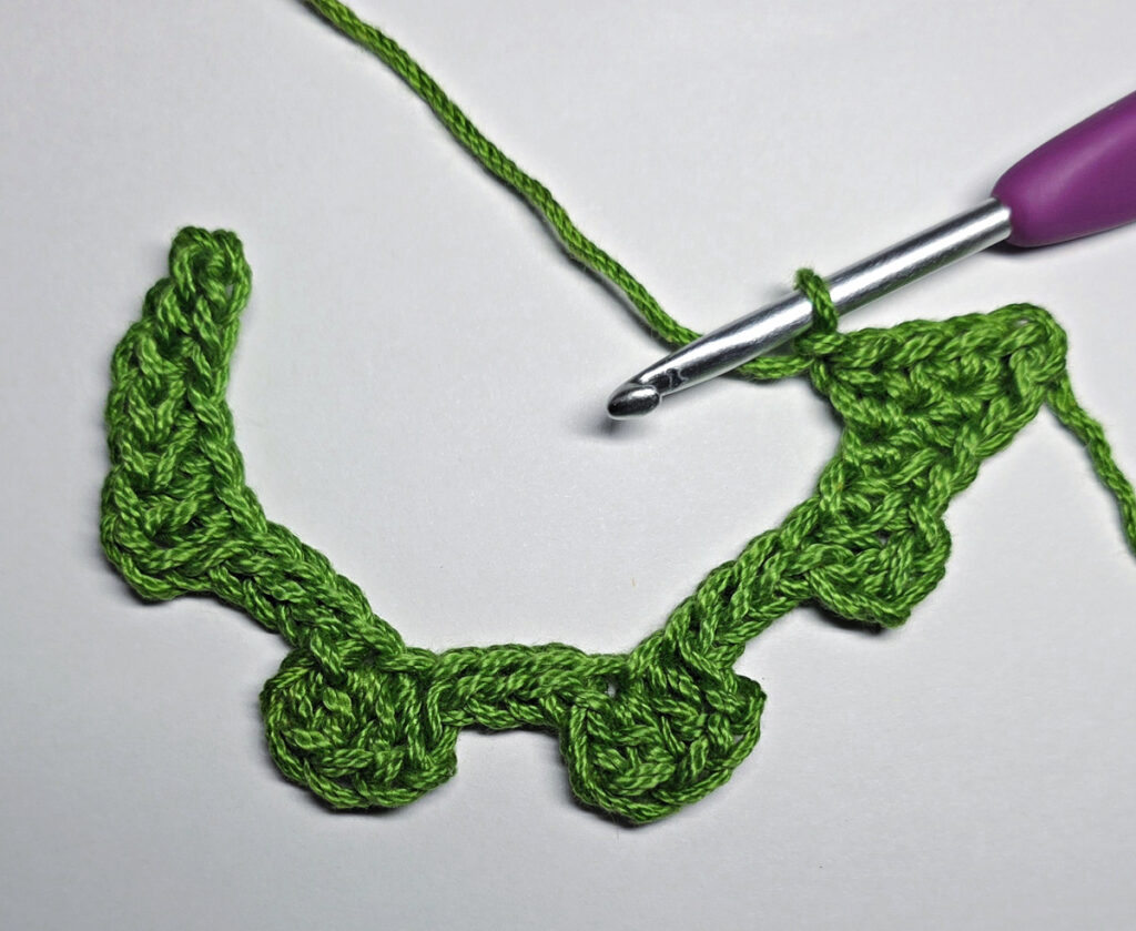 Working up a crochet jack-o-lantern mouth with green yarn.