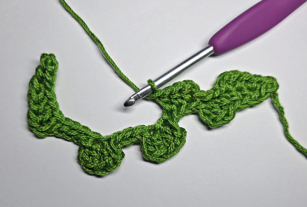 Working up a crochet jack-o-lantern mouth with green yarn.