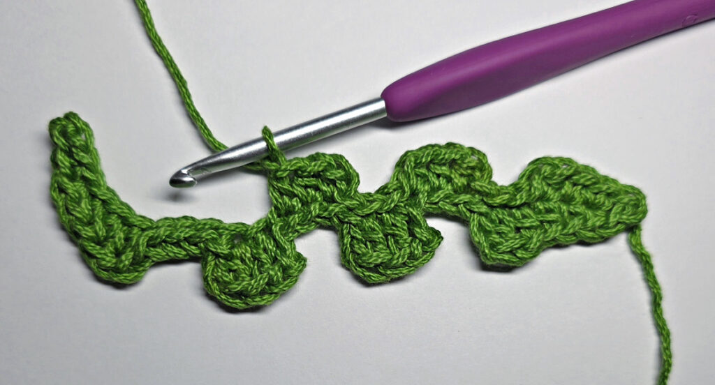 Working up a crochet jack-o-lantern mouth with green yarn.