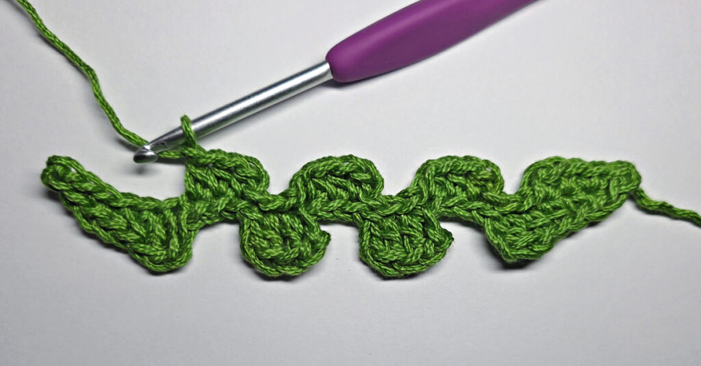 Working up a crochet jack-o-lantern mouth with green yarn.