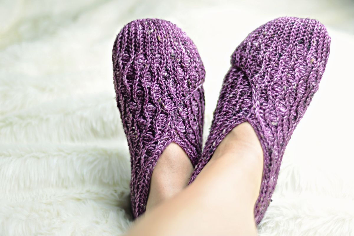 Purple crochet kimono slippers on feet against a white background.