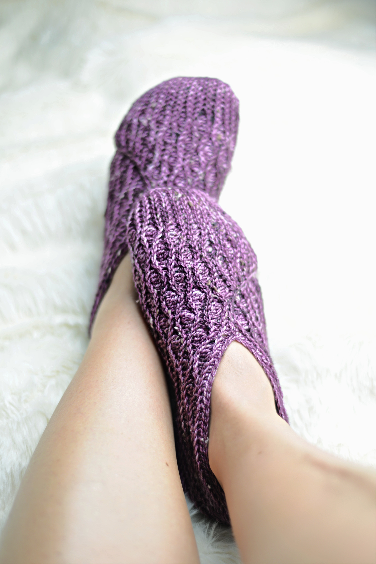 Purple crochet kimono slippers on feet against a white background.