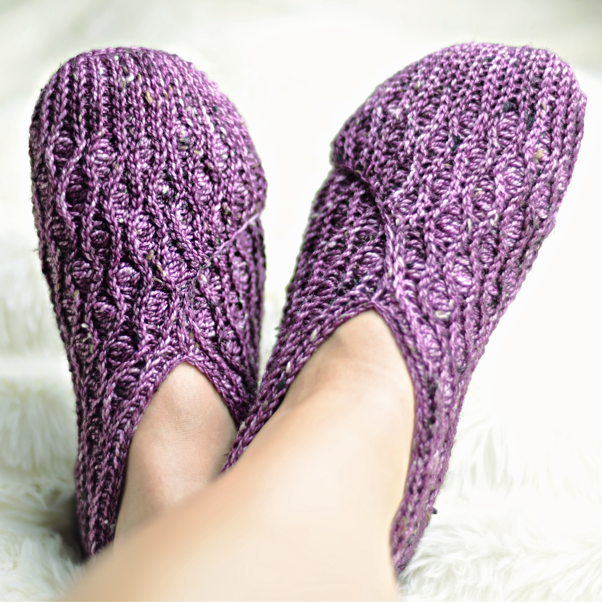 Purple crochet kimono slippers on feet against a white background.