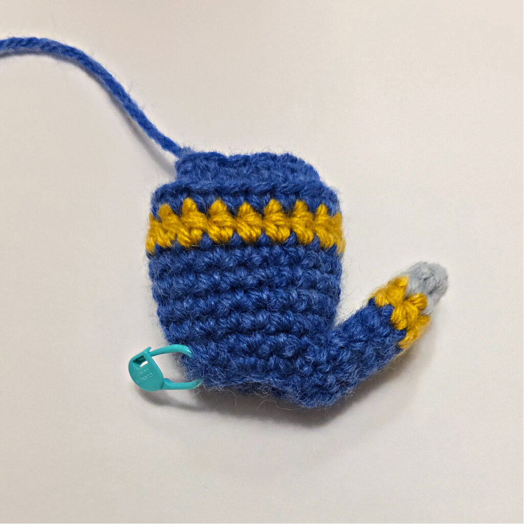 Crocheted blue and yellow shirt with one arm completed.