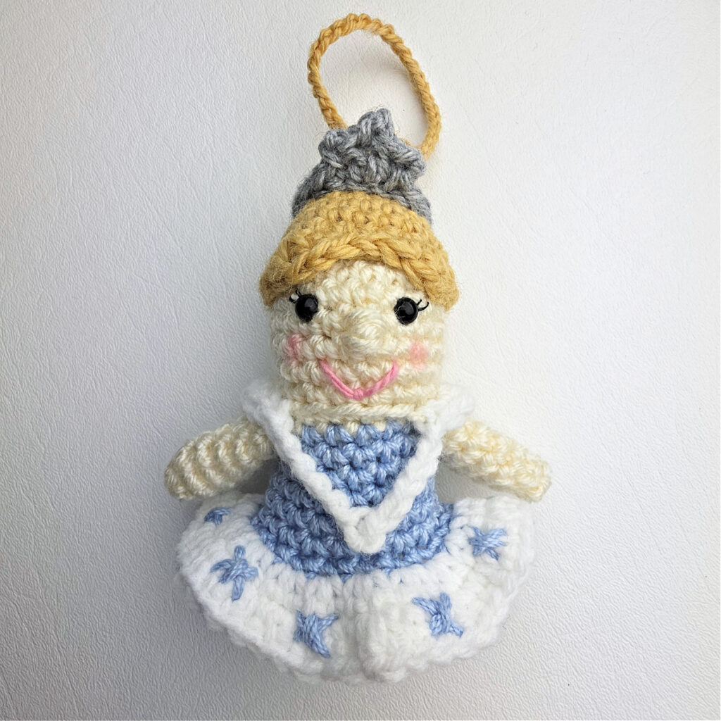 A crochet nutcracker snow queen ornament all ready to be attached to the jingle bell.