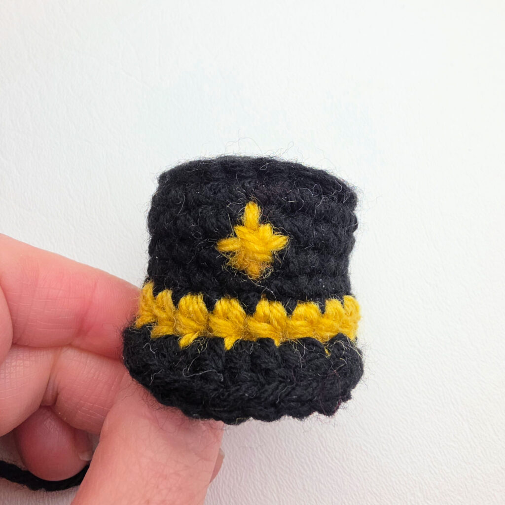 A small black and gold Nutcracker's hat with a gold star.