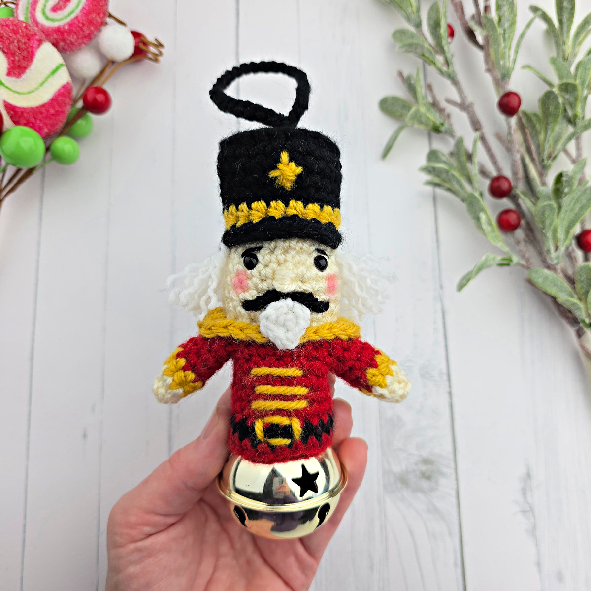Crochet Nutcracker ornament held in a small hand near Christmas decor.