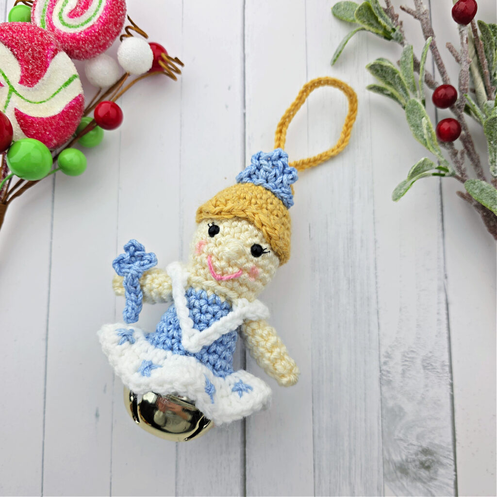 Nutcracker Snow Queen Crochet Ornament with blonde hair and blue tiara on a jingle bell.