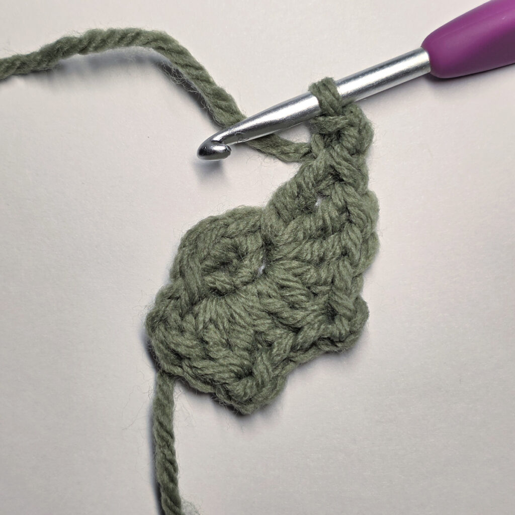Working a green leaf with a purple crochet hook.