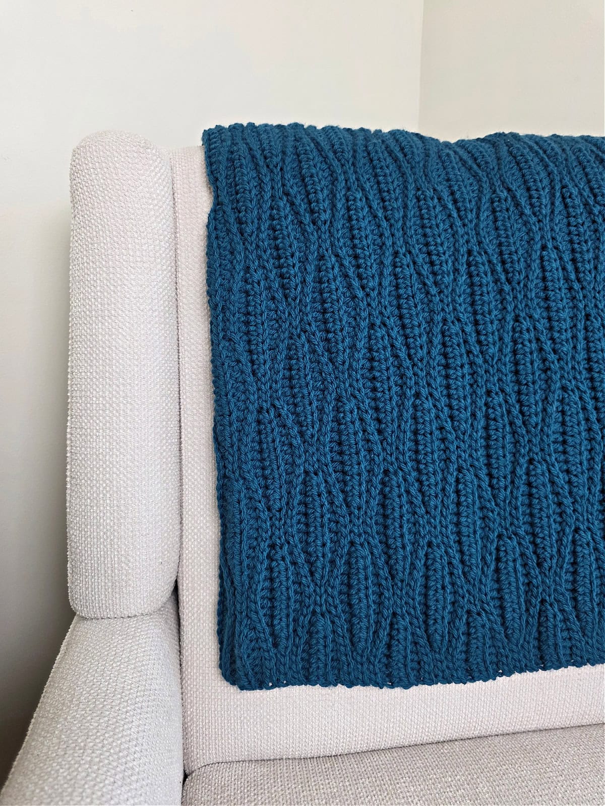A dark blue crochet blanket draped over a sofa chair.