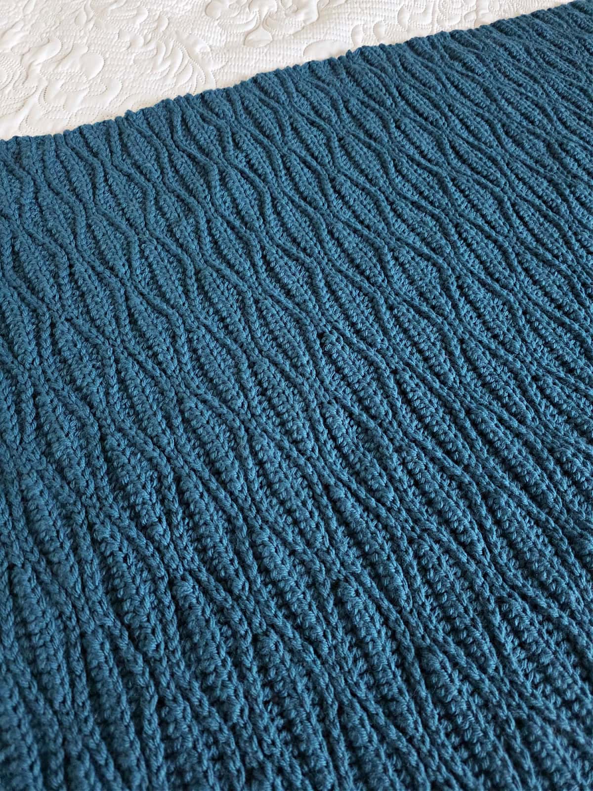 Close up of a dark blue textured crochet blanket.