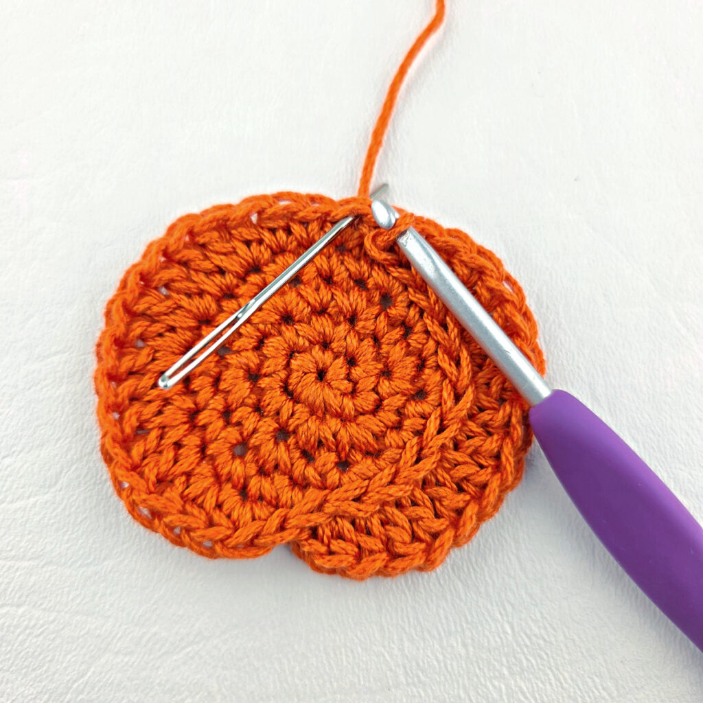 Surface crochet being added to a small crochet pumpkin.
