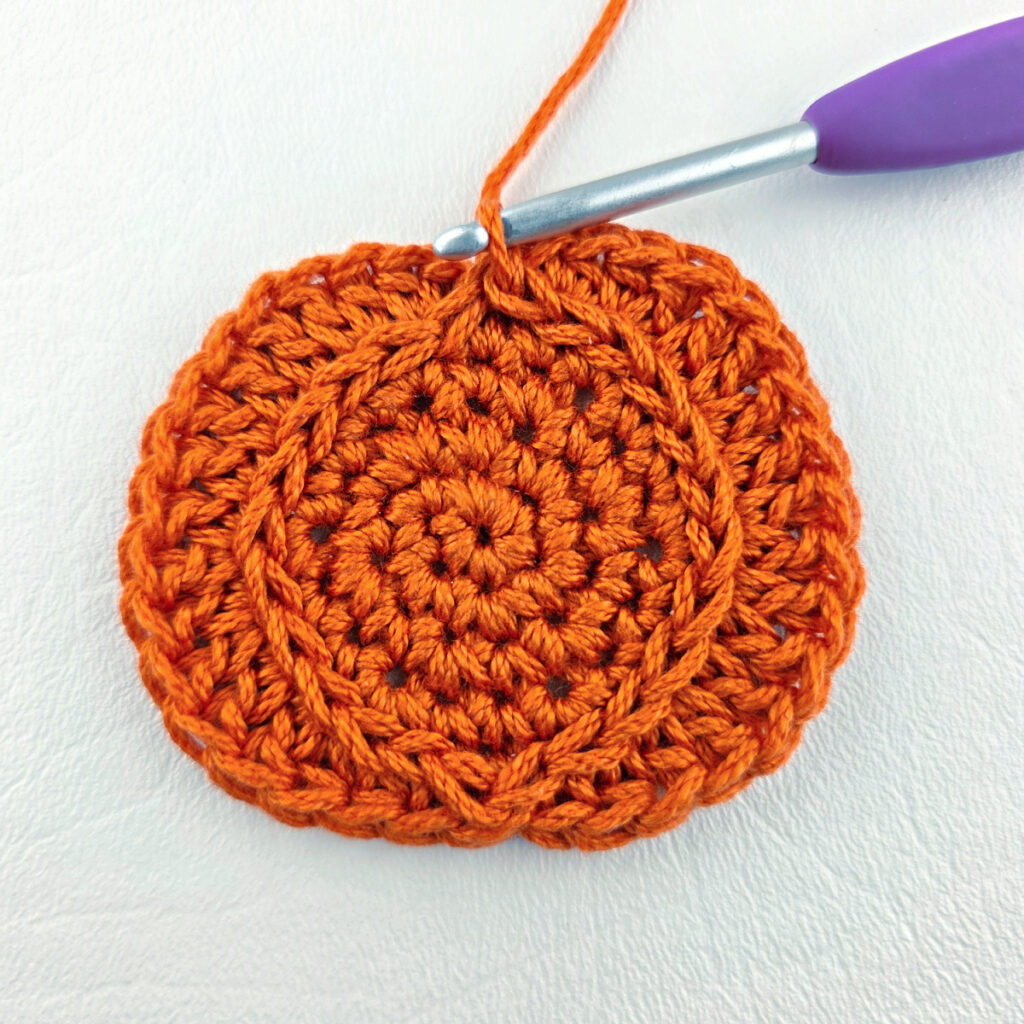 Making a crochet pumpkin applique.