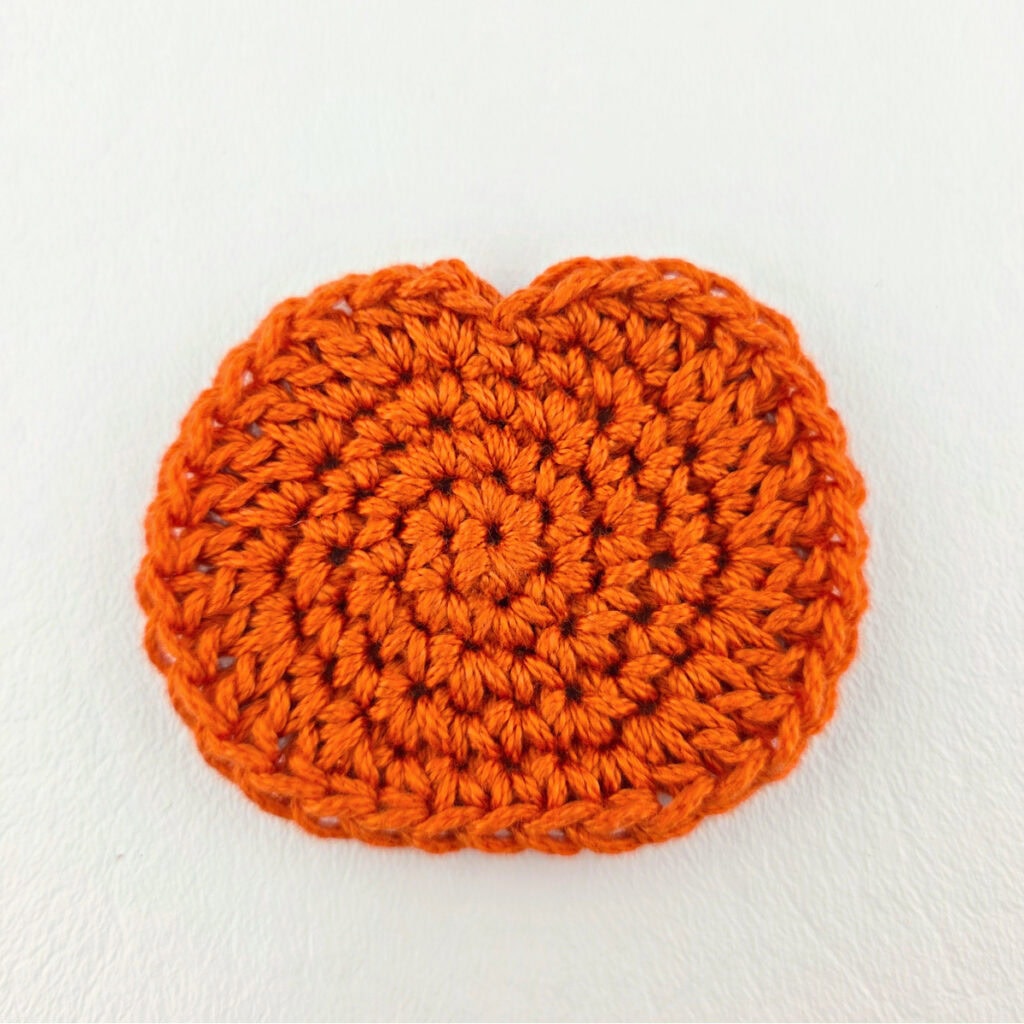 A crochet pumpkin against a white background.