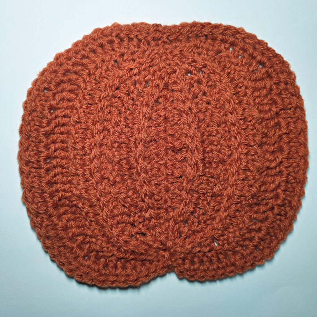 Working an orange crochet pumpkin.