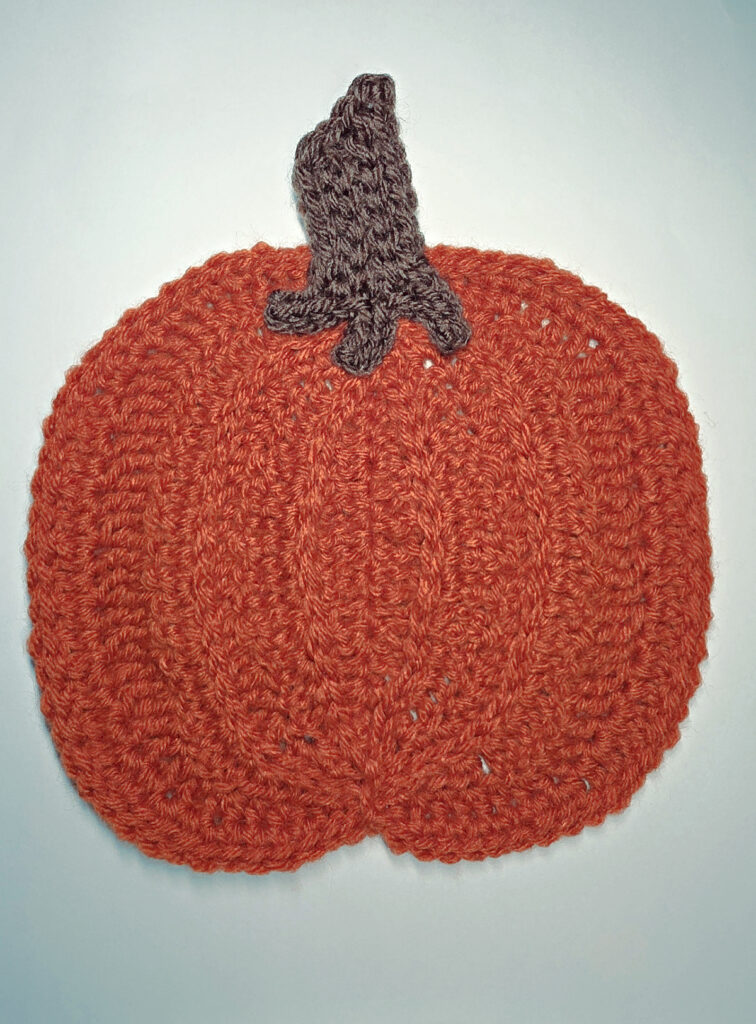 An orange crochet pumpkin with a brown stem.