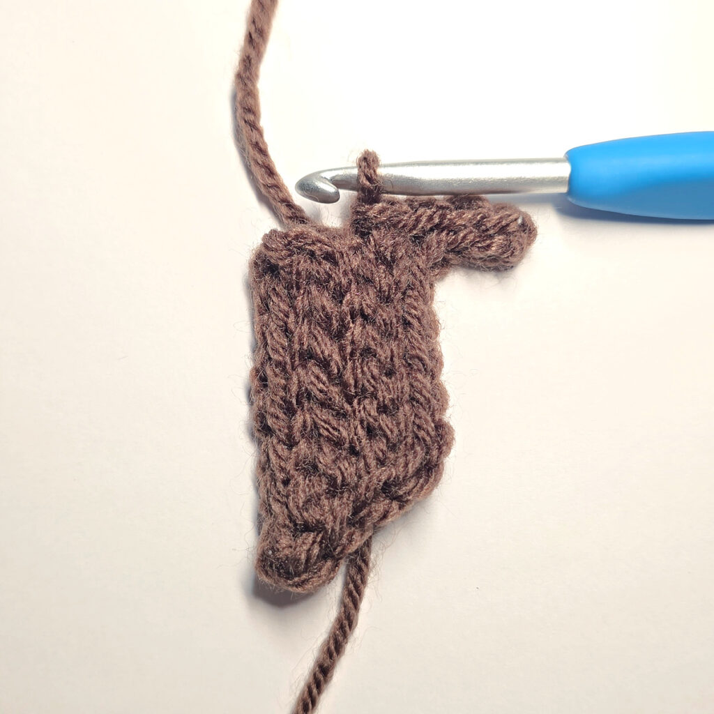 Making a brown crochet pumpkin stem with a blue crochet hook.