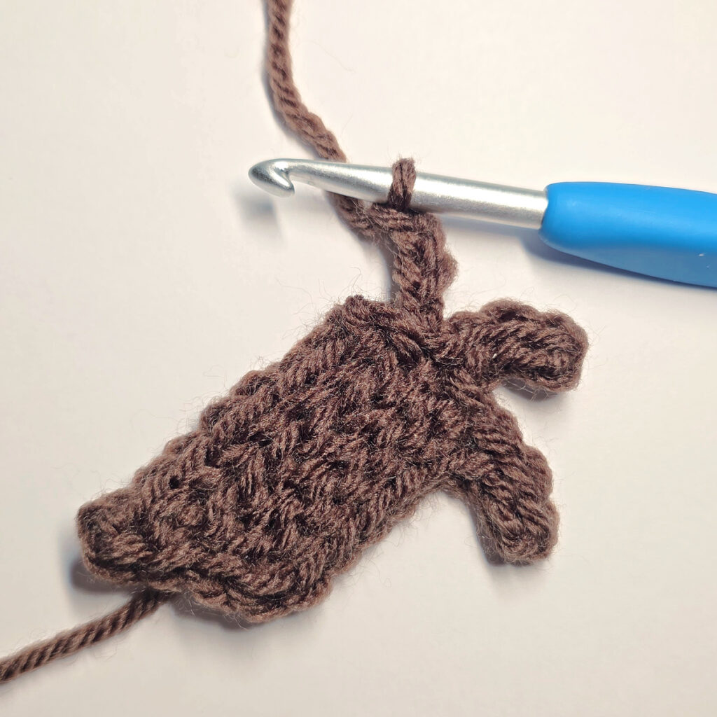 Making a brown crochet pumpkin stem with a blue crochet hook.