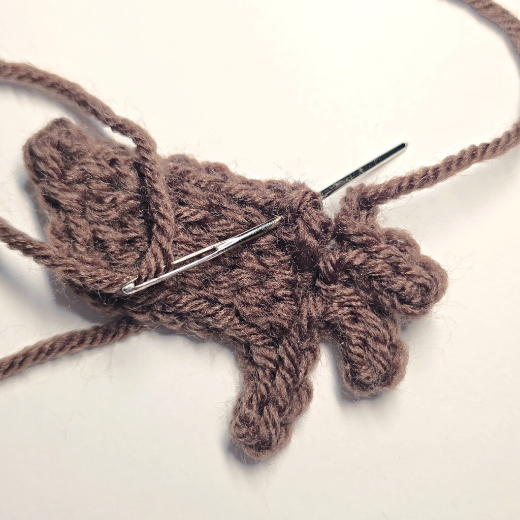 Making a brown crochet pumpkin stem with a blue crochet hook.