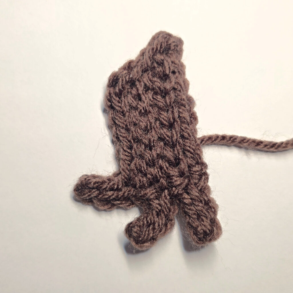 Making a brown crochet pumpkin stem with a blue crochet hook.