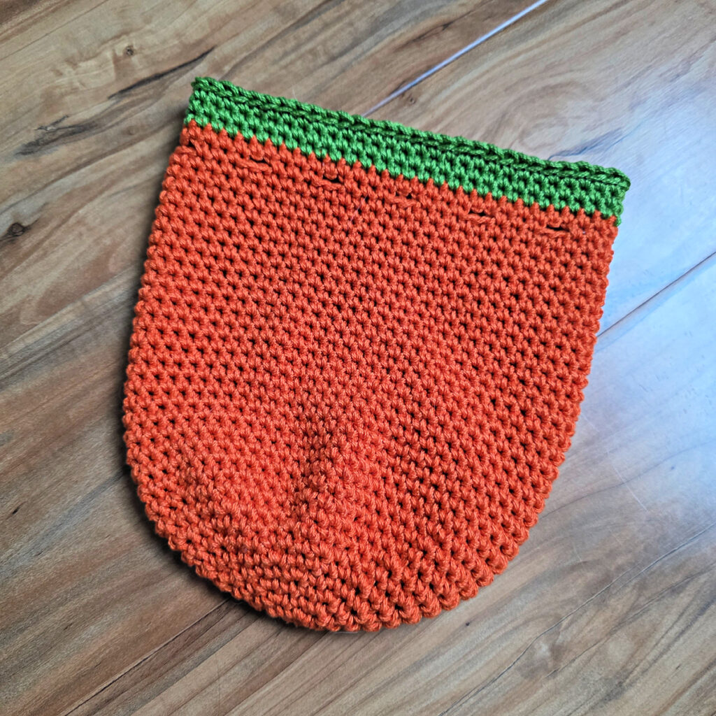 The body of a crochet Jack-O-Lantern pumpkin treat bag.