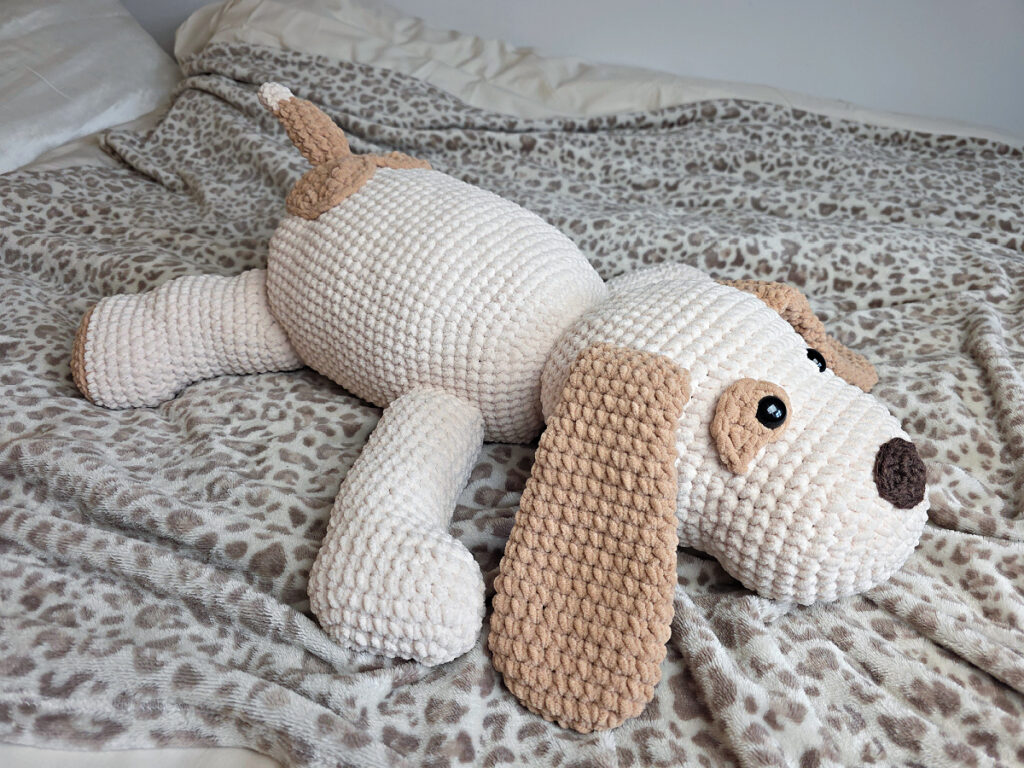 Crochet puppy laying on a leopard print blanket.