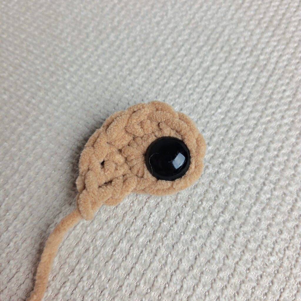 The brown eye patch of a crochet dog.