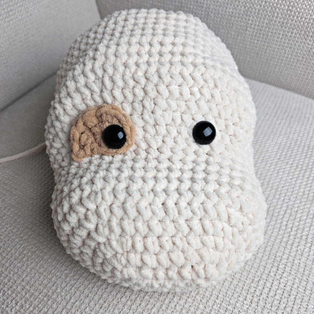 Seaming parts on the head of a plush crochet dog.