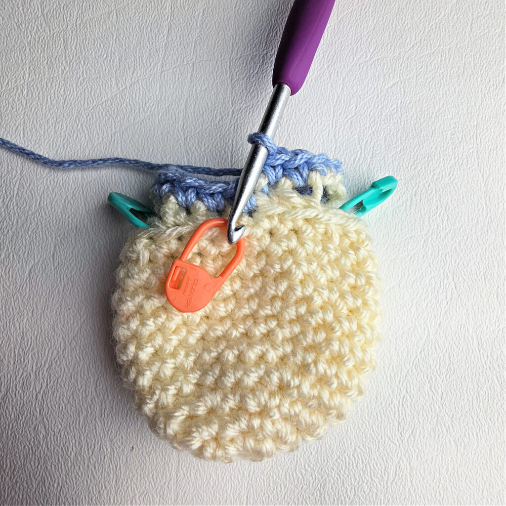 Small ivory crochet head completed in ivory and body started with blue yarn.