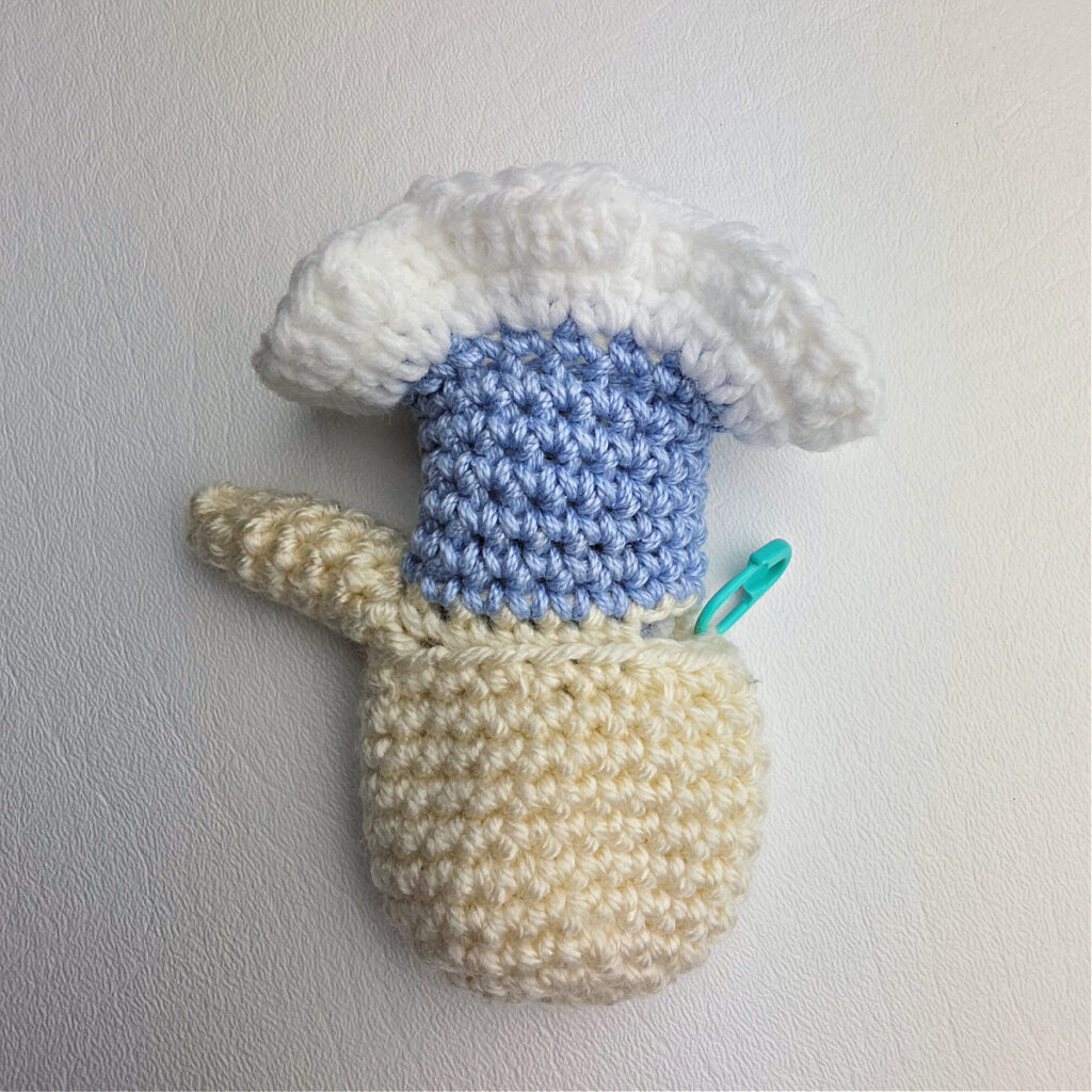 Crochet body upside down with one arm complete and the other just beginning.